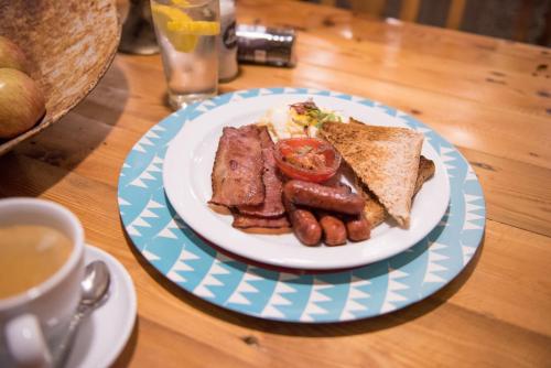 a plate of food with sausage and toast and a cup of coffee at Melrose Place Guestrooms in Potchefstroom