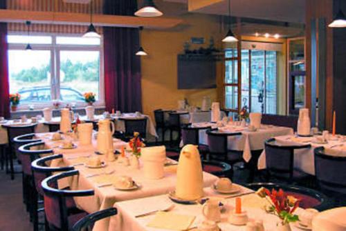une salle à manger avec des tables et des chaises blanches dans l'établissement TOP Motel Sassnitz, à Lanken