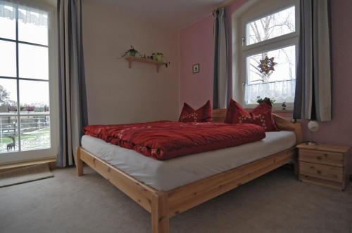 una camera da letto con un letto con lenzuola rosse e una finestra di Landhaus Blumenstein a Mülsen