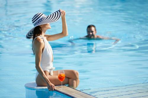 a man and a woman sitting in a swimming pool at Neptune Luxury Resort in Mastihari