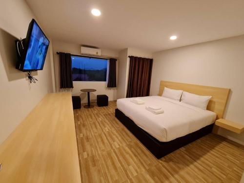 a hotel room with a bed and a flat screen tv at The charlotte smart hotel lopburi in Lop Buri