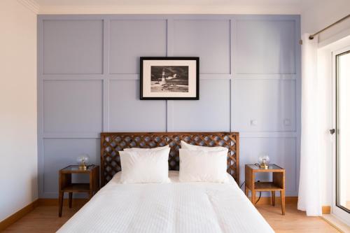 a bedroom with a large white bed with two tables at Casa amigavel do Mar in Sesimbra