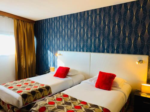 two beds in a hotel room with red pillows at Grand Hôtel de Nîmes 4 étoiles in Nîmes