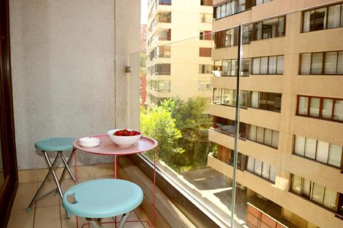 - Balcón con ventana con mesa y 2 sillas en Sunset Aparts, en Santiago