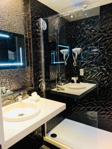 a bathroom with two sinks and a shower at Grand Hôtel de Nîmes 4 étoiles in Nîmes