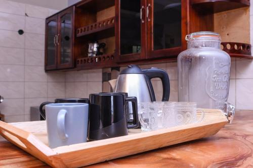 bandeja de madera con tazas y vasos en la encimera de la cocina en Kinzi Apartments Bar & Gardens, en Jinja