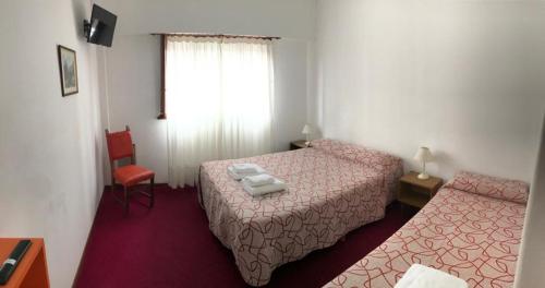 een hotelkamer met 2 bedden en een rode stoel bij Hotel Ser-Mar in San Bernardo