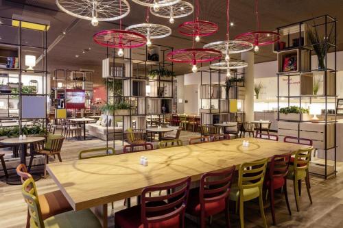 a restaurant with a large wooden table and chairs at IntercityHotel Hildesheim in Hildesheim