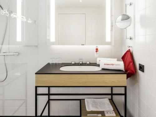 a bathroom with a sink and a mirror at IntercityHotel Hildesheim in Hildesheim