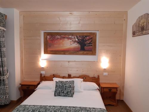 a bedroom with a bed and a picture on the wall at Garnì Valdan in Falcade