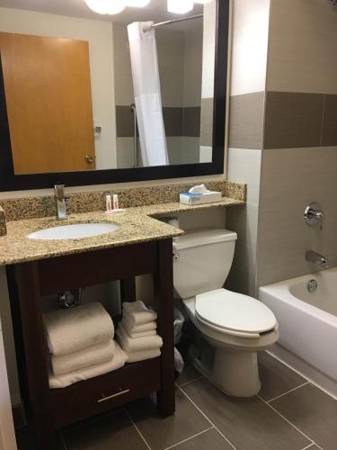 a bathroom with a toilet and a sink and a mirror at Hotel Concord Syracuse in East Syracuse