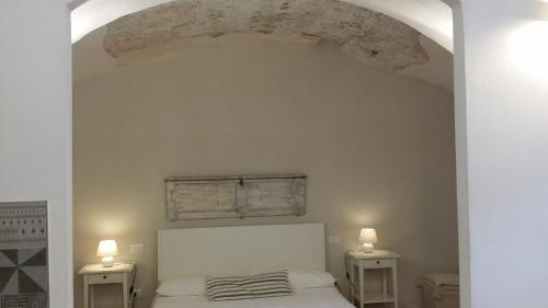 1 dormitorio con 1 cama blanca y 2 mesitas de noche en CASETTE BRIGANTI - monolocali indipendenti con angolo cottura en Gallipoli