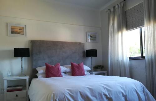 1 dormitorio con 1 cama blanca grande con almohadas rosas en One Above, en Ciudad del Cabo