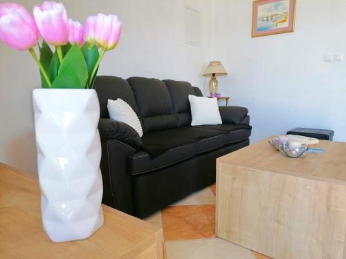 a white vase with pink flowers in a living room at Holiday Home Blue Dream in Putniković