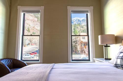 1 dormitorio con 2 ventanas, 1 cama y 1 lámpara en Imogene Hotel, en Ouray