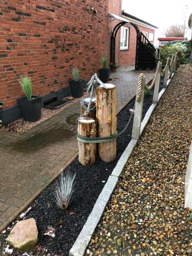 a garden with a wooden stump and a fence at Heimathafen - Ferienwohnung Verse in Eddelak