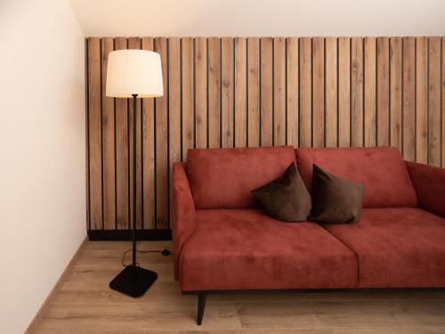a red couch with two pillows on it next to a lamp at Residence Iris in Valdaora