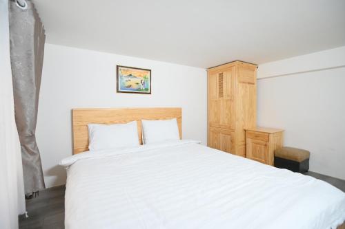 a bedroom with a white bed and a wooden cabinet at Villa SEVENBAY in Da Lat