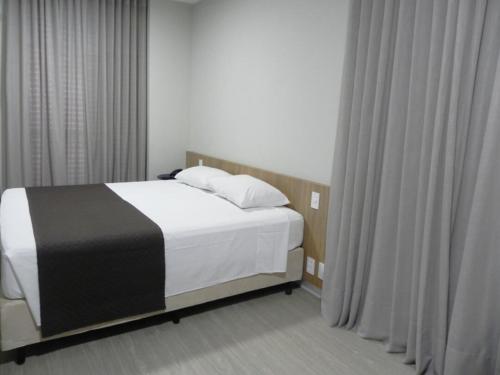 um quarto com uma cama com lençóis brancos e pretos em Rio Branco Hotel em Florianópolis