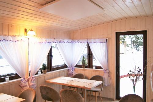 a dining room with a table and chairs and windows at Villa Paula in Polanica-Zdrój