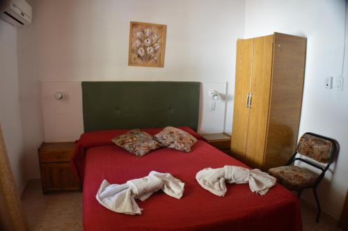 1 dormitorio con 1 cama roja y 2 toallas en Hosteria Norca en La Falda