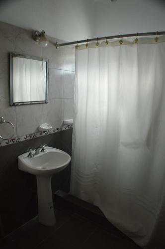 a bathroom with a white shower curtain and a sink at Hosteria Norca in La Falda
