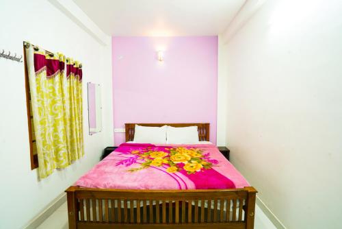 um quarto com uma cama com um cobertor rosa em MSP Amma Cottage em Munnar