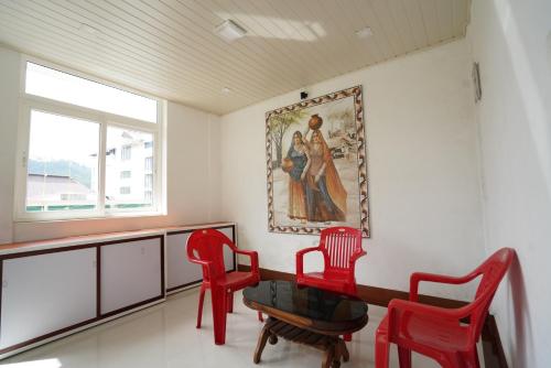 una habitación con 2 sillas rojas y un cuadro en la pared en MSP Amma Cottage, en Munnar