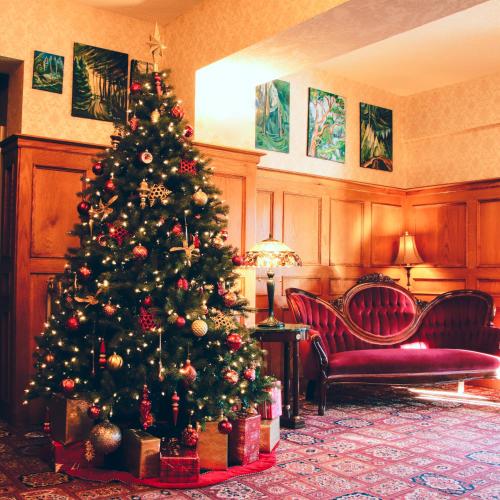 a christmas tree in a living room with presents at James Bay Inn Hotel, Suites & Cottage in Victoria