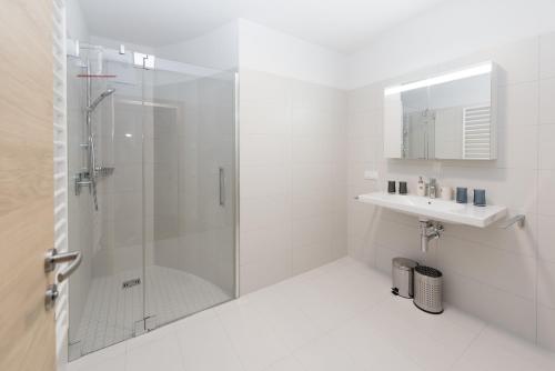 a white bathroom with a shower and a sink at Apartments Bergleben Goldegg in Goldegg