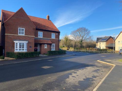 a red brick house on the side of a street at Stansted Coach House - Apartment Hotel in Elsenham
