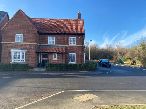 a red brick house with a car parked in the driveway at Stansted Coach House - Apartment Hotel in Elsenham