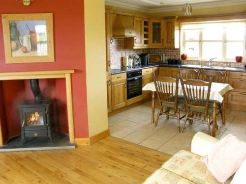 a kitchen with a fireplace and a table with chairs at Scenic Estuary Way Home in Labasheeda in Labasheeda