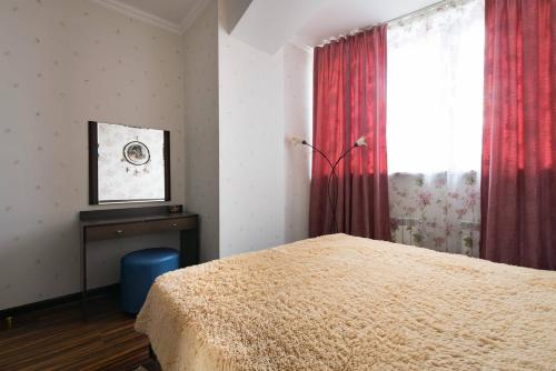 a bedroom with a bed and a window with red curtains at Nadezhda Apartments in Keremet on Timiryazev street 1 in Almaty