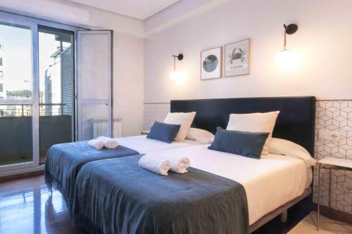 a bedroom with a large bed with towels on it at The Rentals Collection - Erribera in San Sebastián