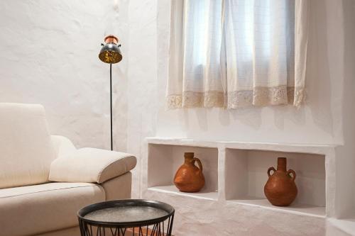 a living room with a couch and two vases at Habitaciones y Apartamentos en el centro La Jábega by Conil Home in Conil de la Frontera