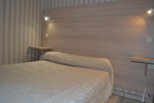 a bedroom with a bed and a wooden wall at Hotel Concorde in Nîmes