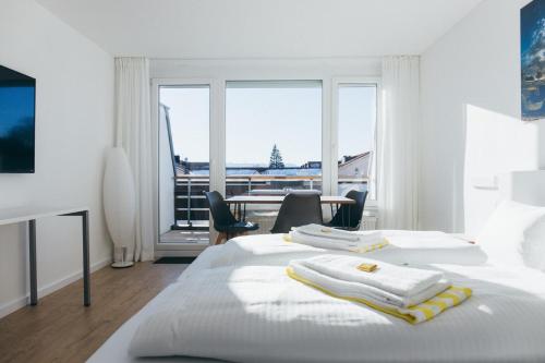 a white bedroom with two beds and a table and chairs at HEIMATEL - Ferienwohnungen in Scheidegg