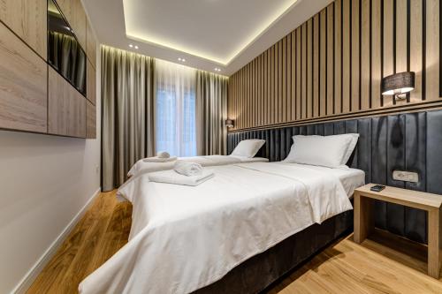 um quarto com uma cama grande e lençóis brancos em Apart Compliment em Podgorica