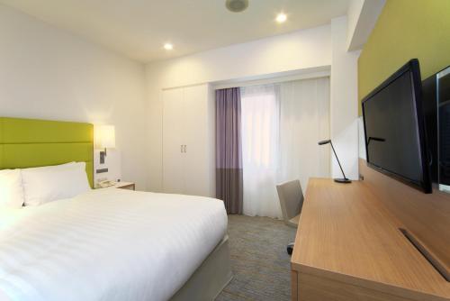 a hotel room with a bed and a flat screen tv at ANA Holiday Inn Sapporo Susukino by IHG in Sapporo