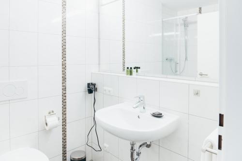 a white bathroom with a sink and a mirror at HEIMATEL - Suiten, Apartments und Studios in Scheidegg