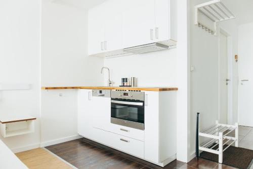 a kitchen with white cabinets and a stove top oven at HEIMATEL - Suiten, Apartments und Studios in Scheidegg