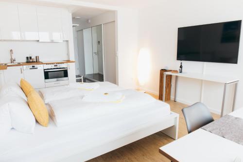 a white room with a white couch and a tv at HEIMATEL - Suiten, Apartments und Studios in Scheidegg