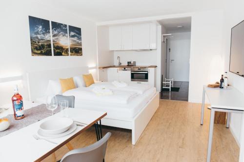 a white living room with a white couch and a table at HEIMATEL - Suiten, Apartments und Studios in Scheidegg