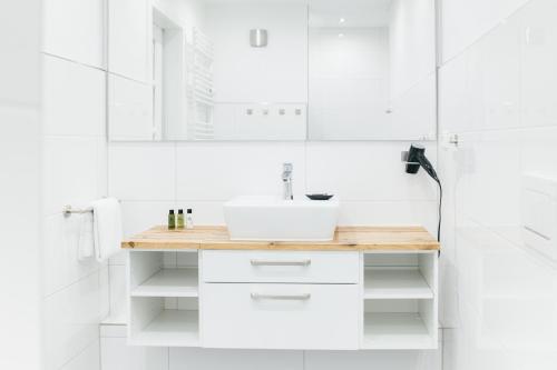 a white bathroom with a sink and a mirror at HEIMATEL - Suiten, Apartments und Studios in Scheidegg