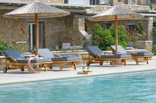a patio area with chairs, tables and umbrellas at AC Village Christoulis in Mikonos
