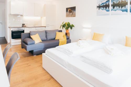 a white living room with a couch and a table at HEIMATEL - Suiten, Apartments und Studios in Scheidegg