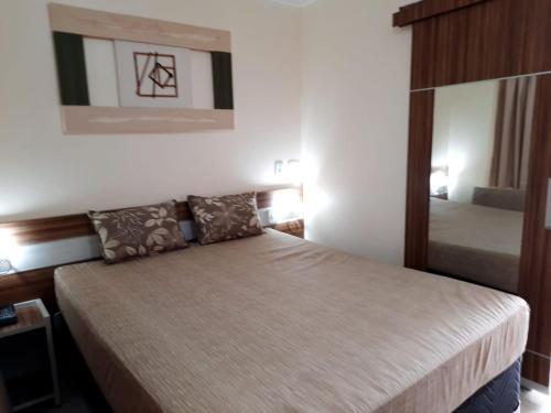 1 dormitorio con cama y espejo en Lacqua Diroma - Apartamentos Completos, en Caldas Novas