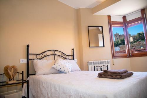a bedroom with a bed with white sheets and a window at MEQUEDO CASA PILARCHO in Alcañiz