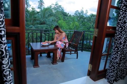 a woman sitting at a table on a balcony at Hill View Resort in Nakandalagoda